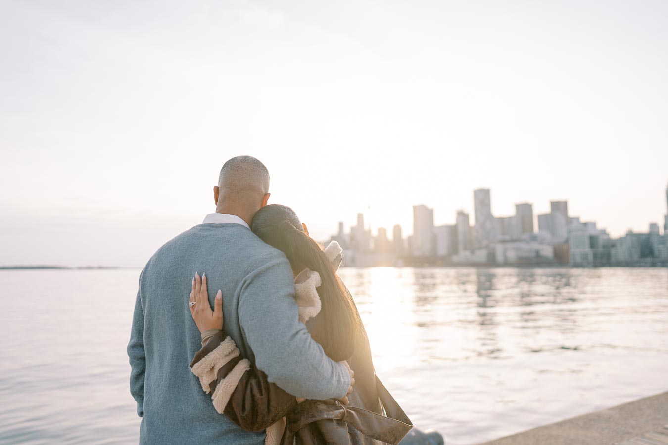 Couple hugging at Toronto waterfront during engagement session at sunset