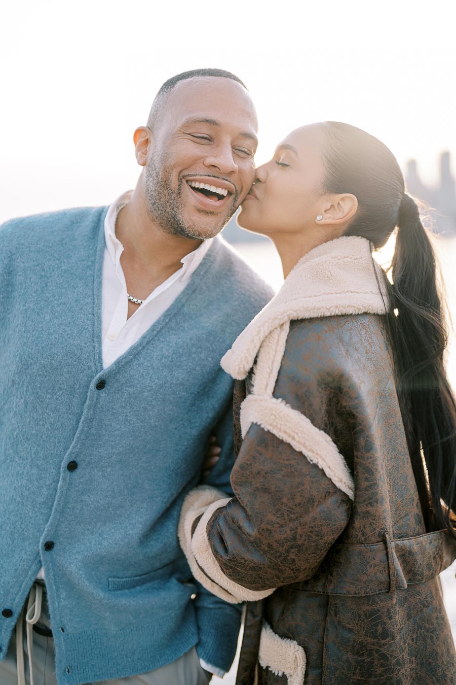 Bride-to-be kissing fiancé on the cheek during joyful engagement session in Toronto