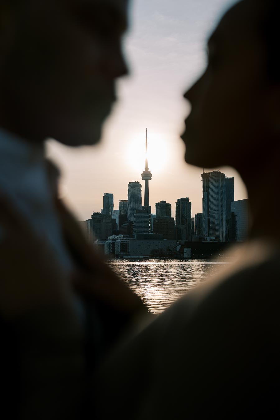 CN Tower framed between blurred silhouettes of DeVon Franklin and Maria Castillo at sunset