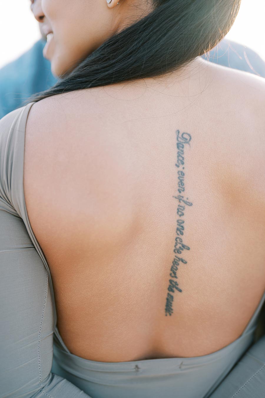 Tattoo on Maria Castillo’s back reading “Dance even if no one else hears the music”