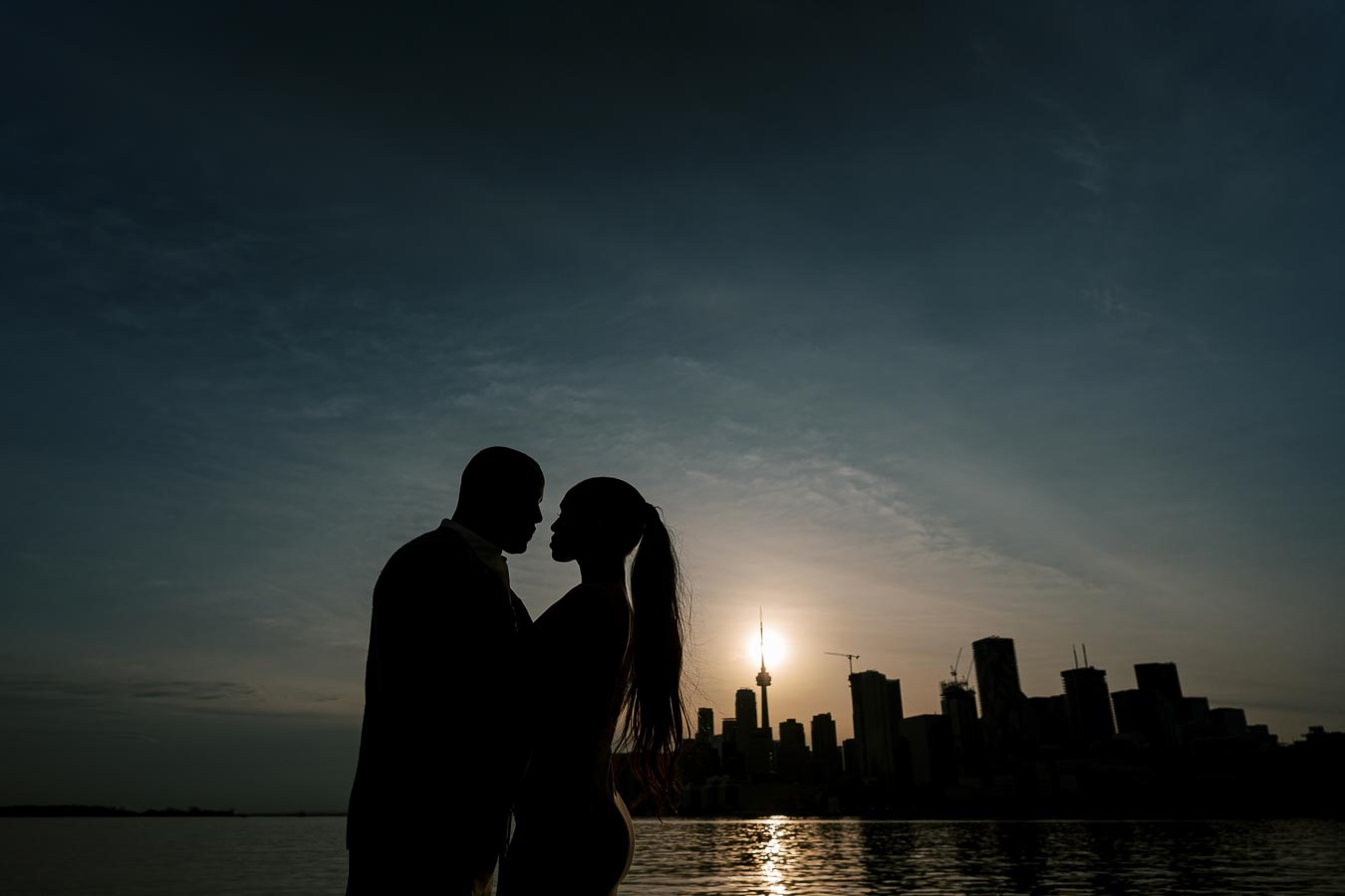 Silhouette of DeVon Franklin and Maria Castillo at sunset with Toronto skyline in the background