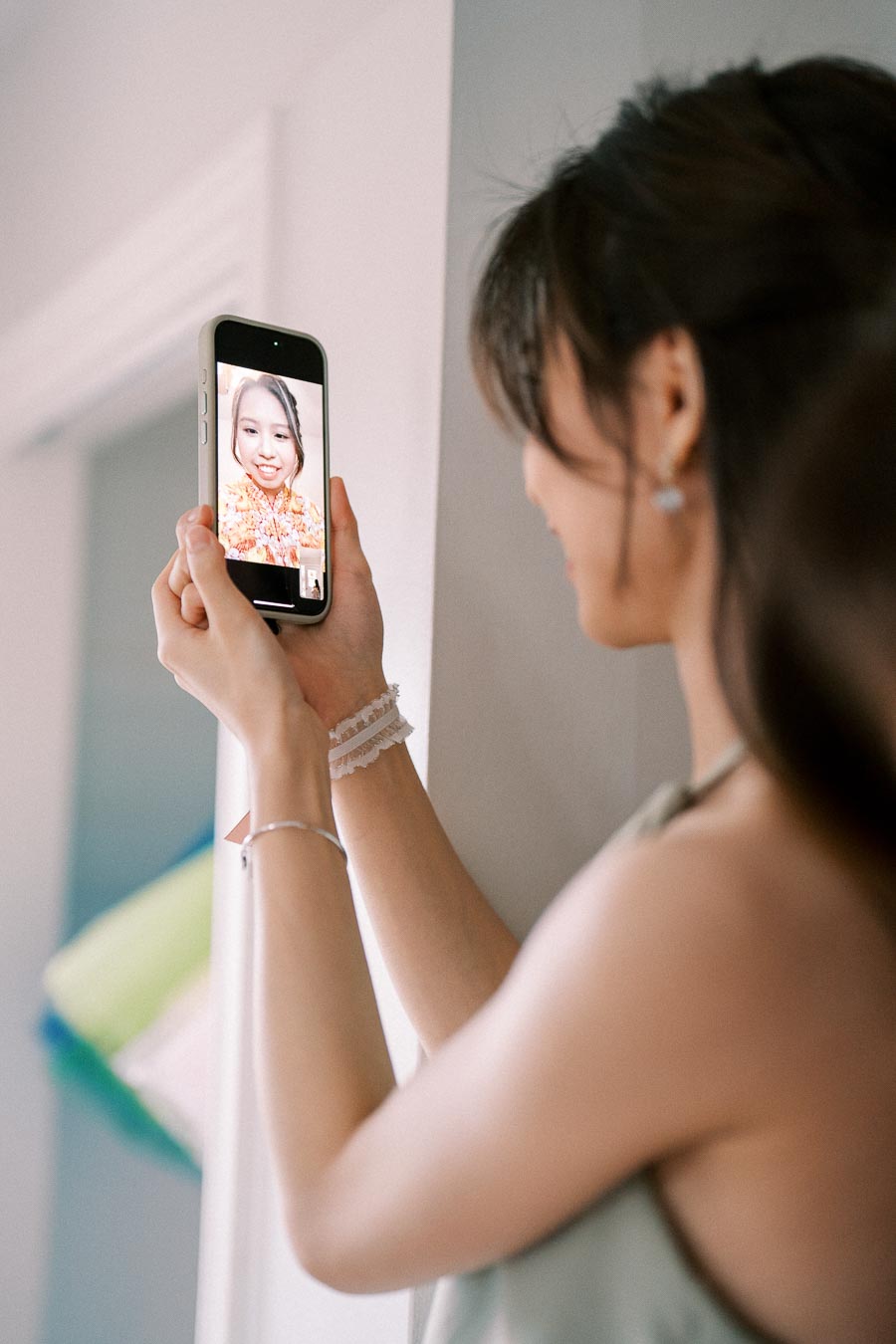 A woman holding a smartphone and engaging in a video call with another woman who is smiling and wearing a floral outfit.