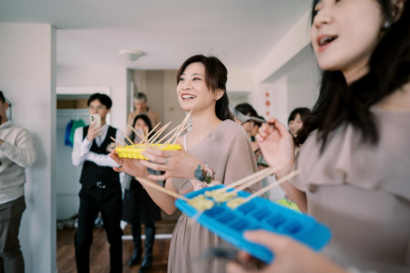 Young woman enjoying a lively gathering with friends, participating in a fun ice cube tray game at a social event indoors.