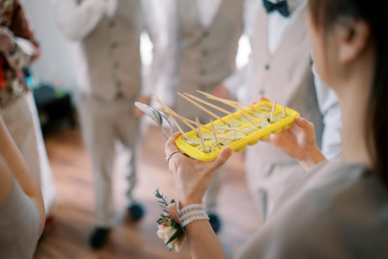 Wedding guests participating in a fun activity with a yellow ice cube tray filled with green liquid and skewers.