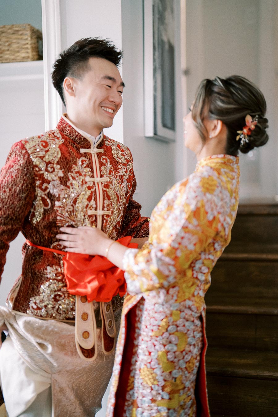 Couple in Traditional Asian Wedding Attire Smiling at Each Other Indoors