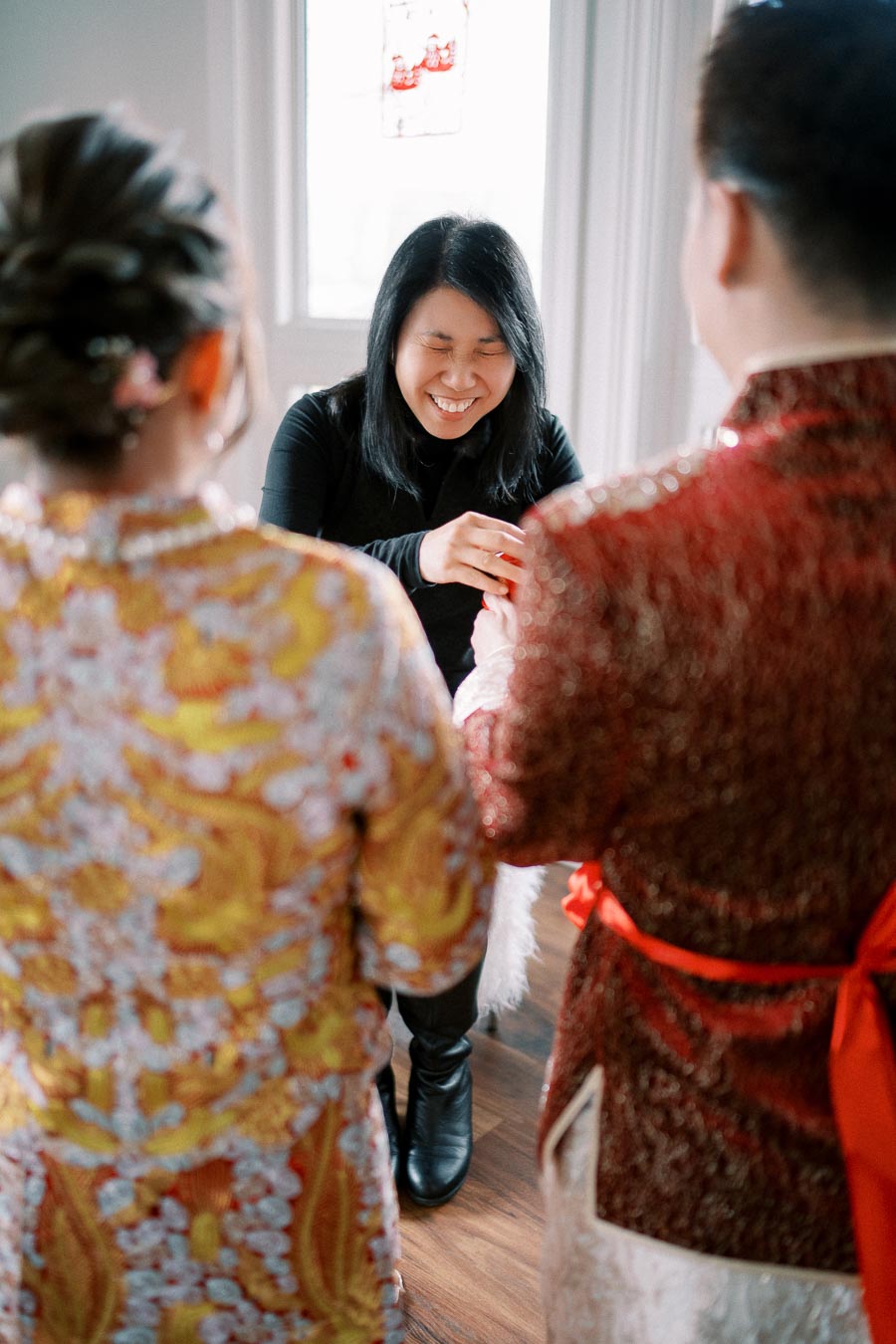 Couple in traditional Chinese attire participating in a joyful ceremony with an officiant, highlighting cultural traditions and celebration.