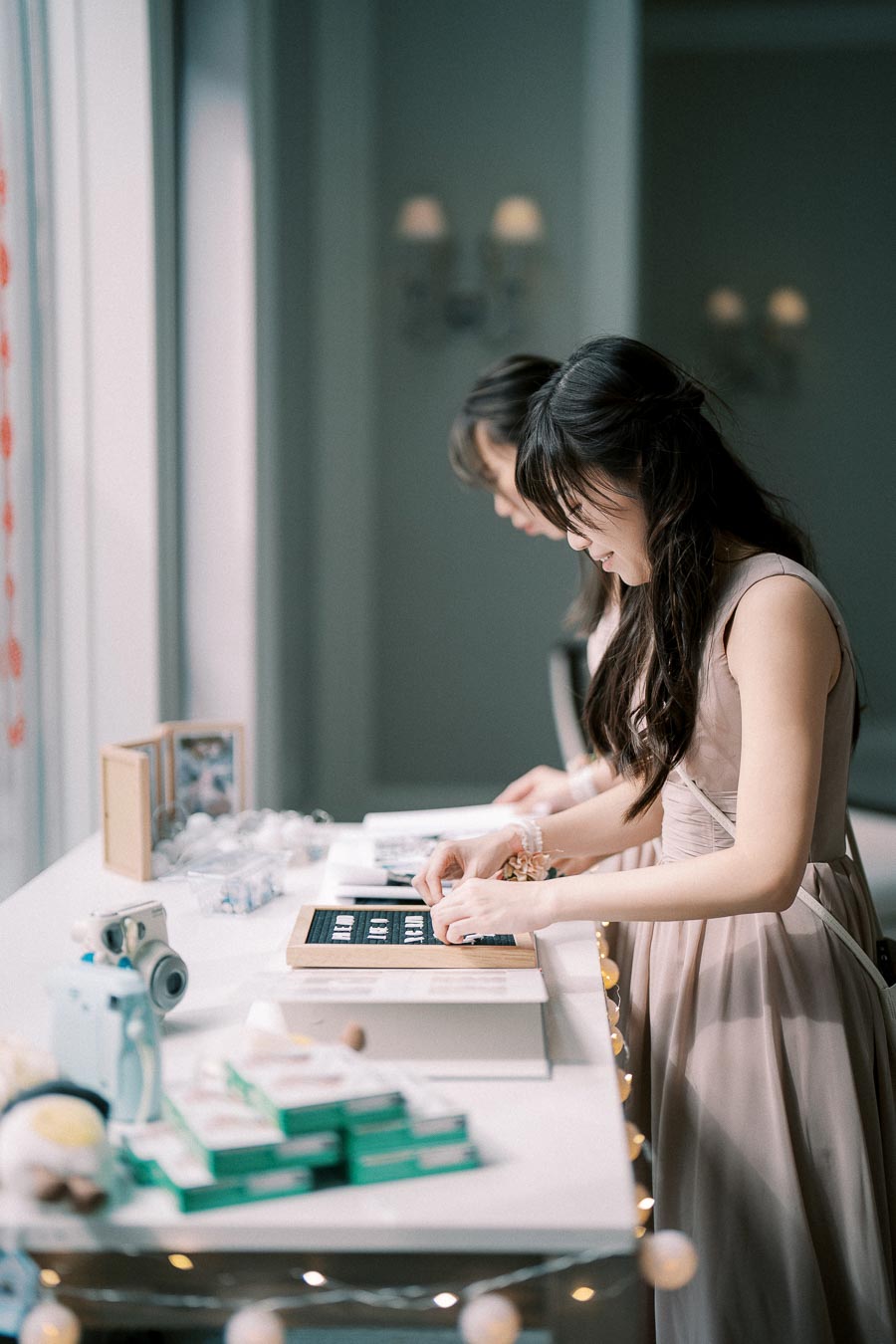 Young women crafting name cards at a decorative table during an indoor event.