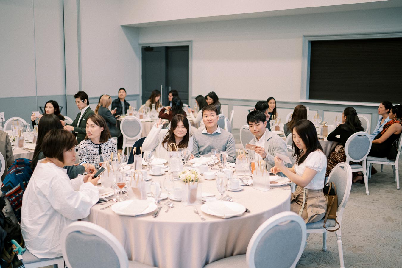 A group of people enjoy a formal dining event, seated at round tables in an elegantly decorated banquet hall.