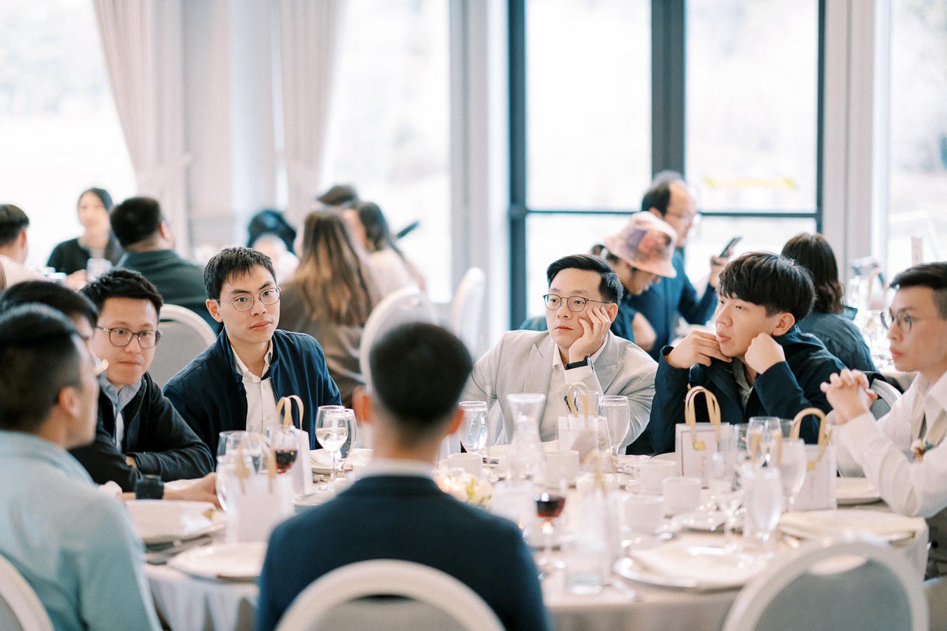 A group of people sitting around a table in a formal meeting or event, with drinks and glasses visible, engaged in discussion in a well-lit room.