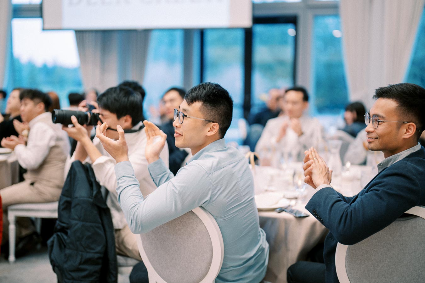 Audience clapping and taking photos at a conference event, highlighting engagement and participation.
