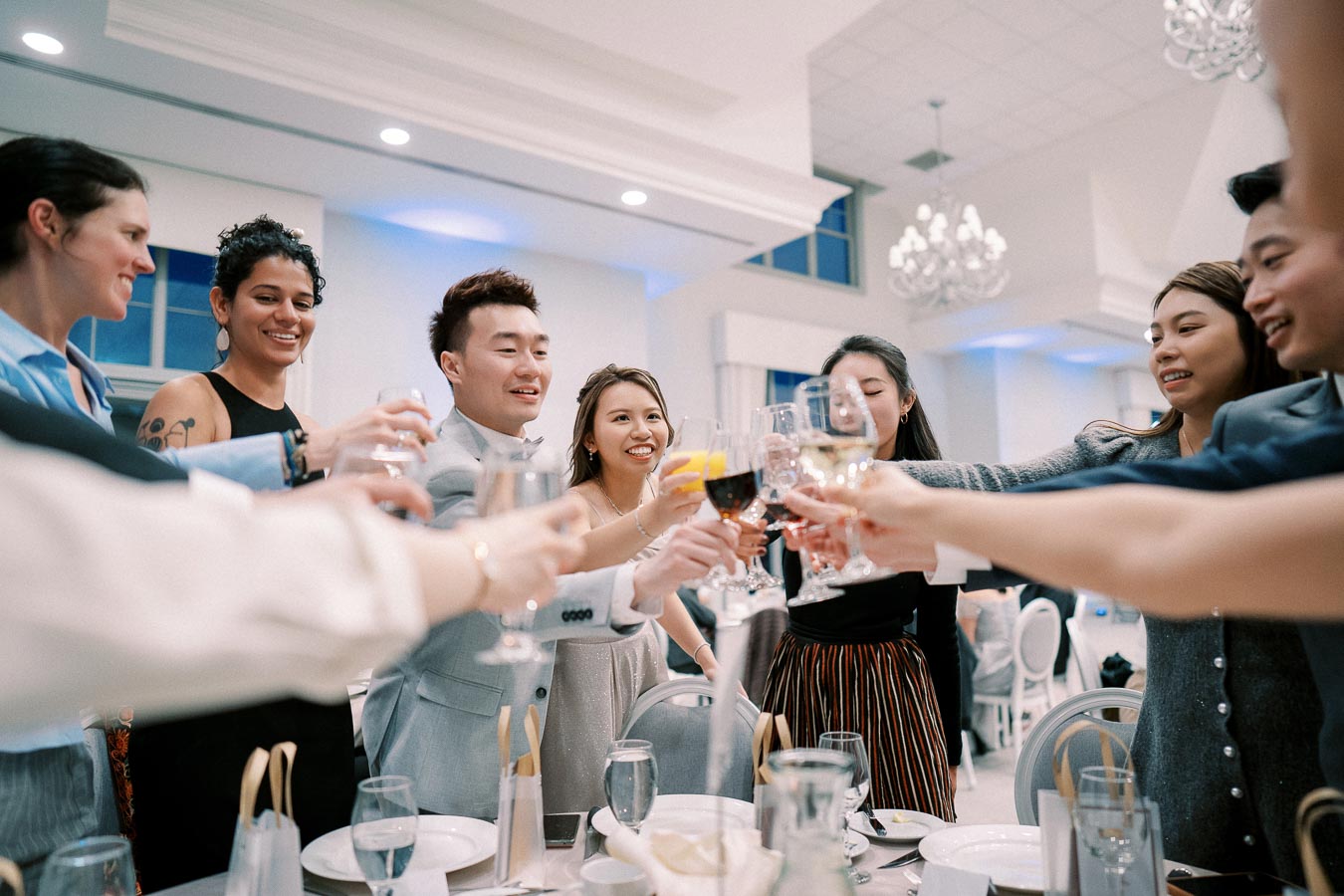 A group of friends joyfully toasting with wine glasses at a celebratory dinner party in an elegant venue.