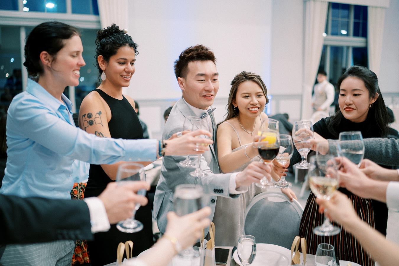 A group of friends raising glasses for a toast at an indoor celebration, capturing joyful expressions and a festive atmosphere.