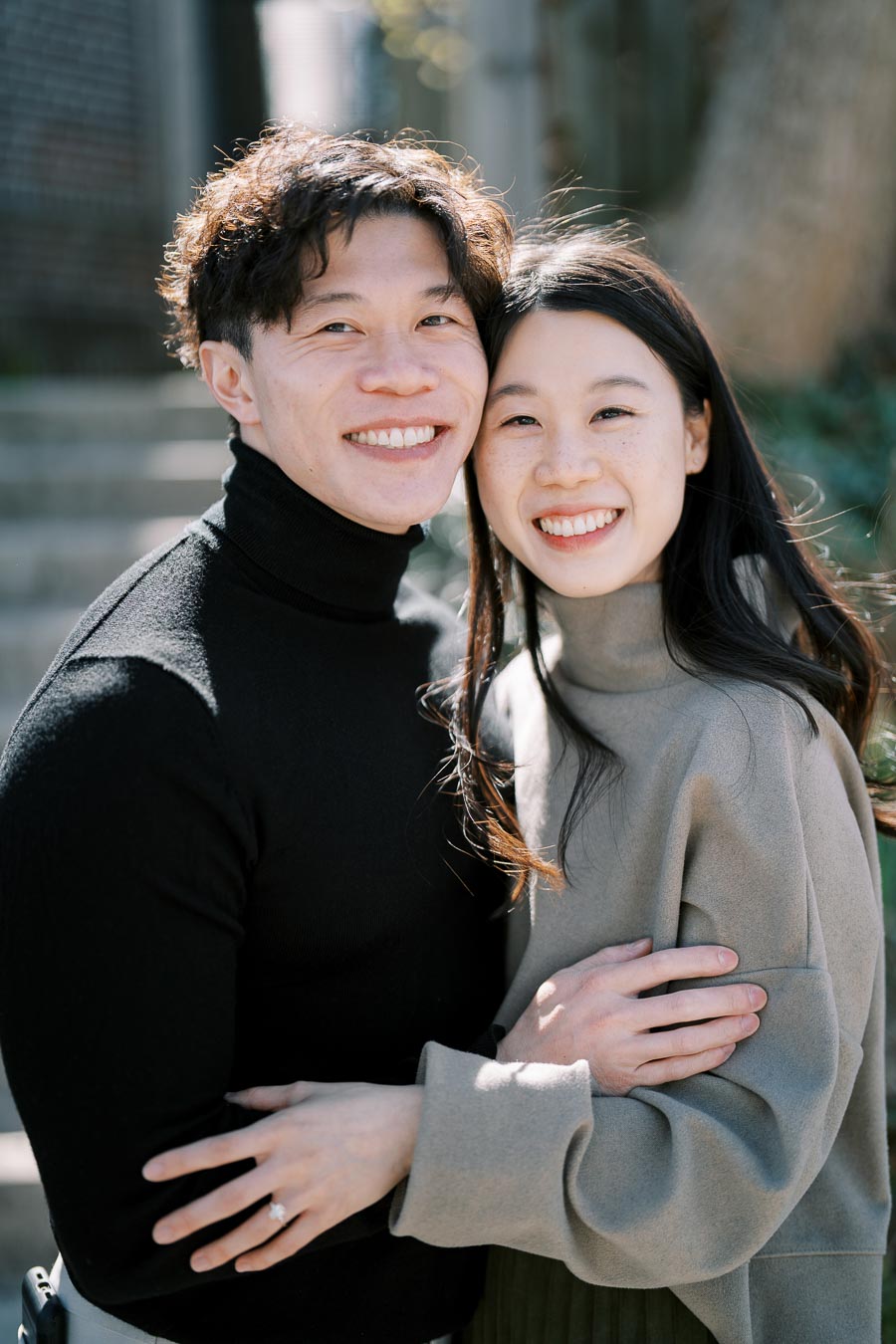 A happy couple embraces outdoors, showcasing their smiles and affection for each other.