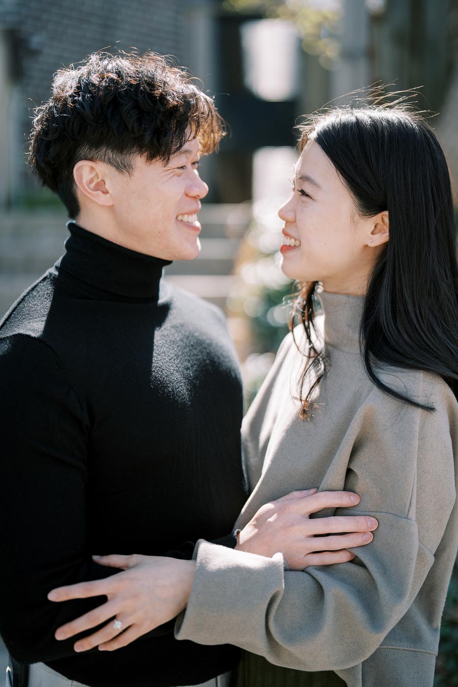 A couple shares a joyful moment outdoors, gazing into each other's eyes with smiles.