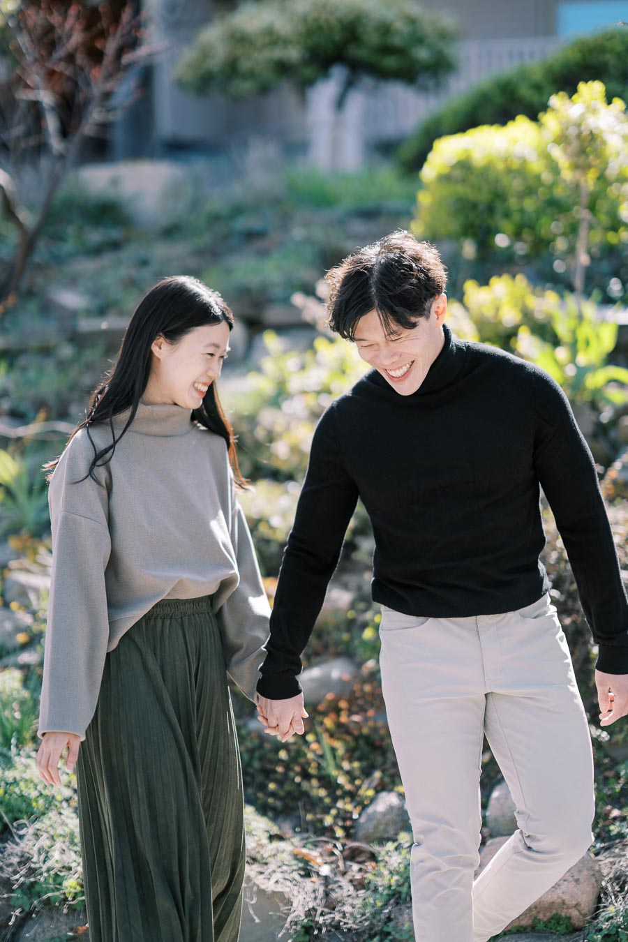A couple enjoys a sunny day outdoors, walking hand in hand and sharing smiles.