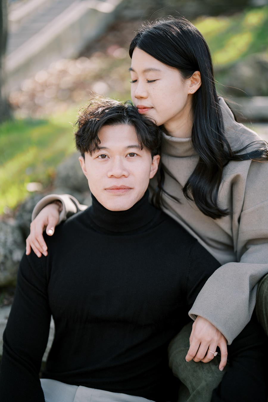 A serene moment captured between a couple sitting outdoors, with the woman gently resting her head on the man's shoulder.