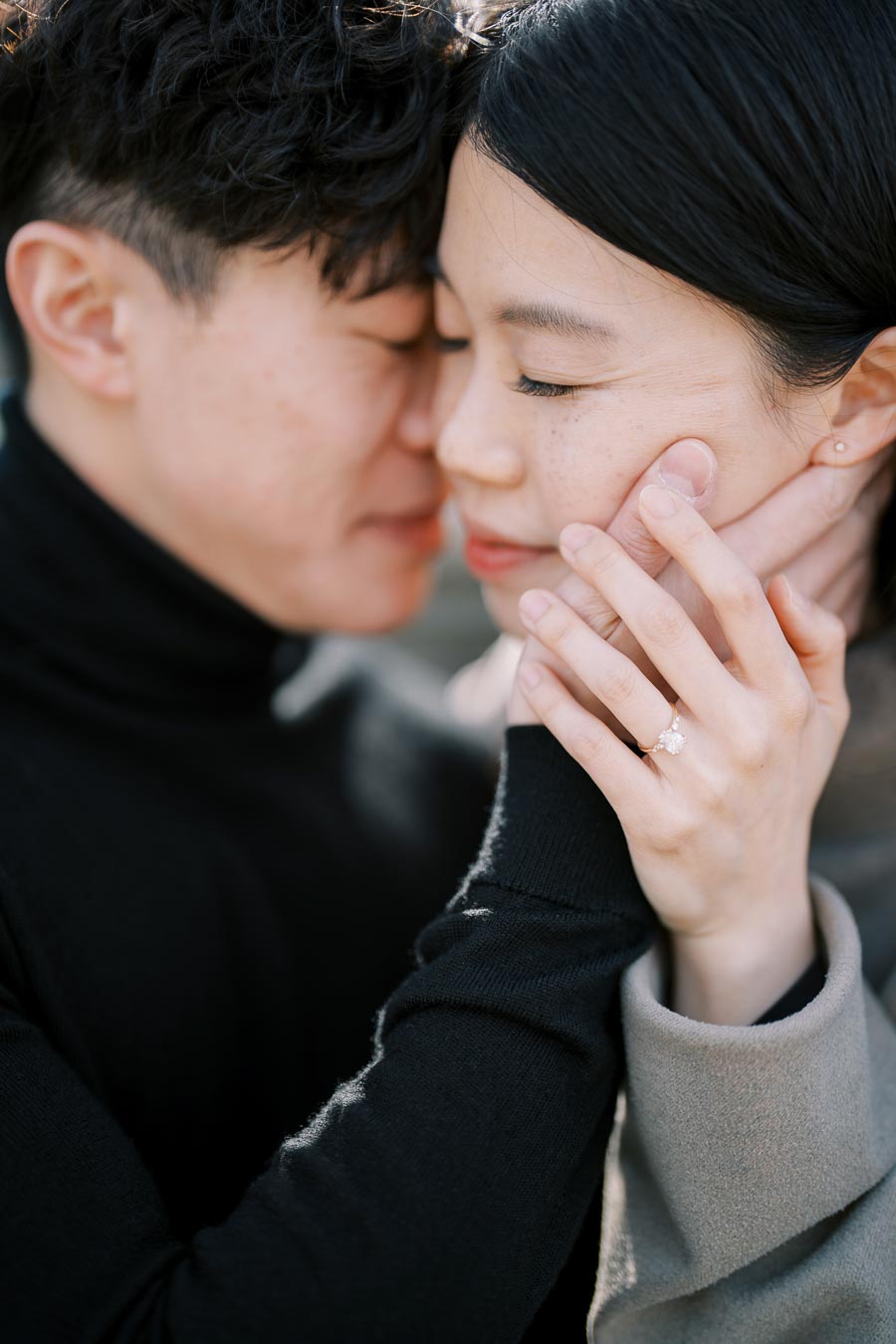 A close-up shot of a couple sharing an intimate moment, highlighting the woman's engagement ring.