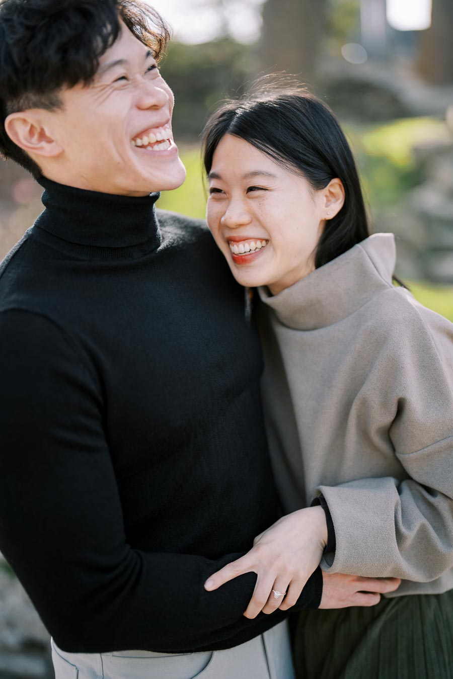 A joyful couple shares a moment of laughter and affection outdoors.