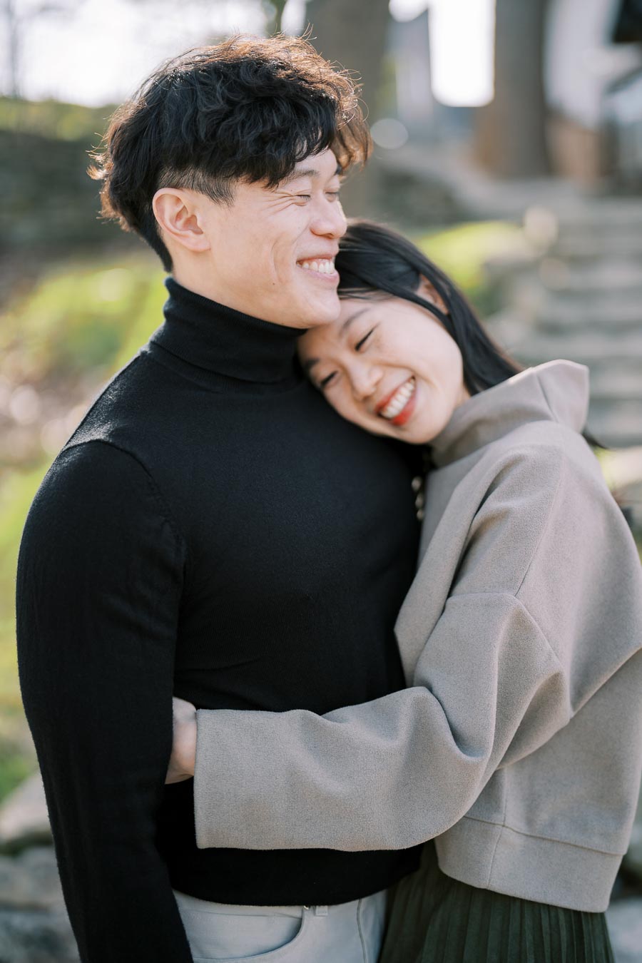 A joyful couple embracing outdoors, enjoying a sunny day.