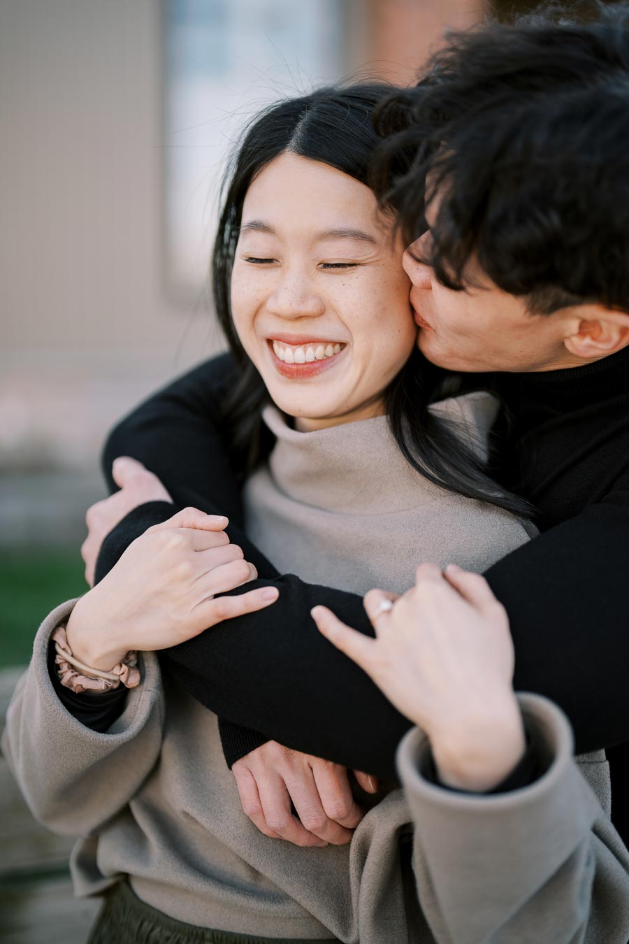 A joyful moment captured between a couple as the man kisses the woman's cheek, making her smile.