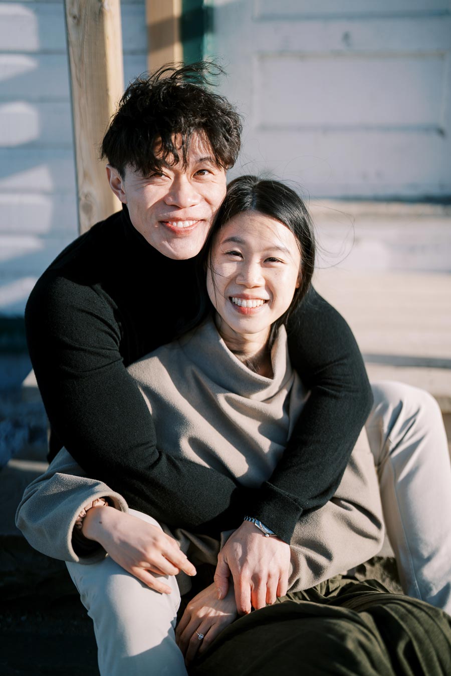 A happy couple enjoying a sunny day outdoors, embracing and smiling at the camera.