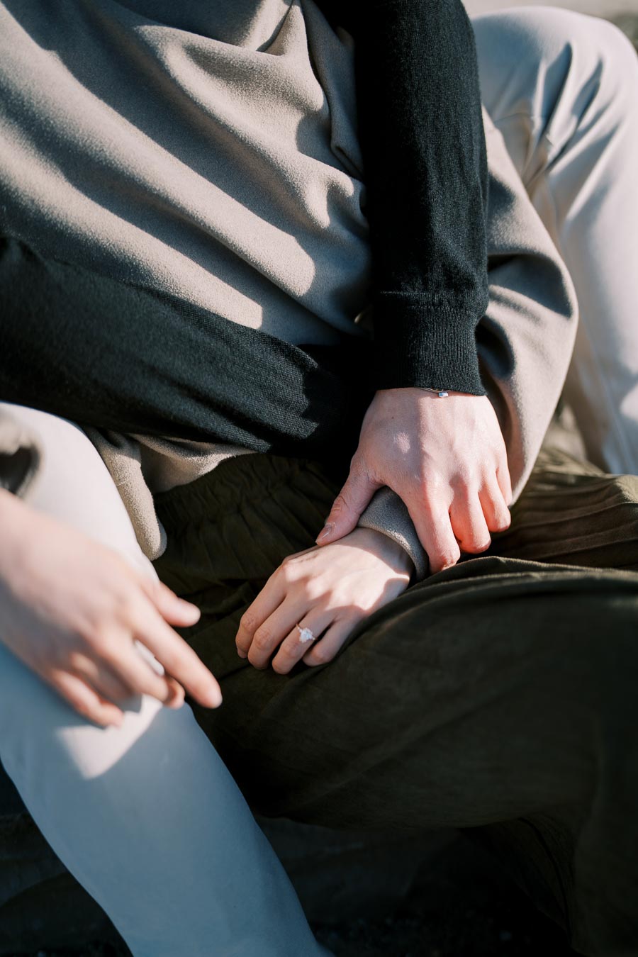 A close-up of two people sitting together, with one person wearing a ring on their finger, suggesting a moment of intimacy or engagement.