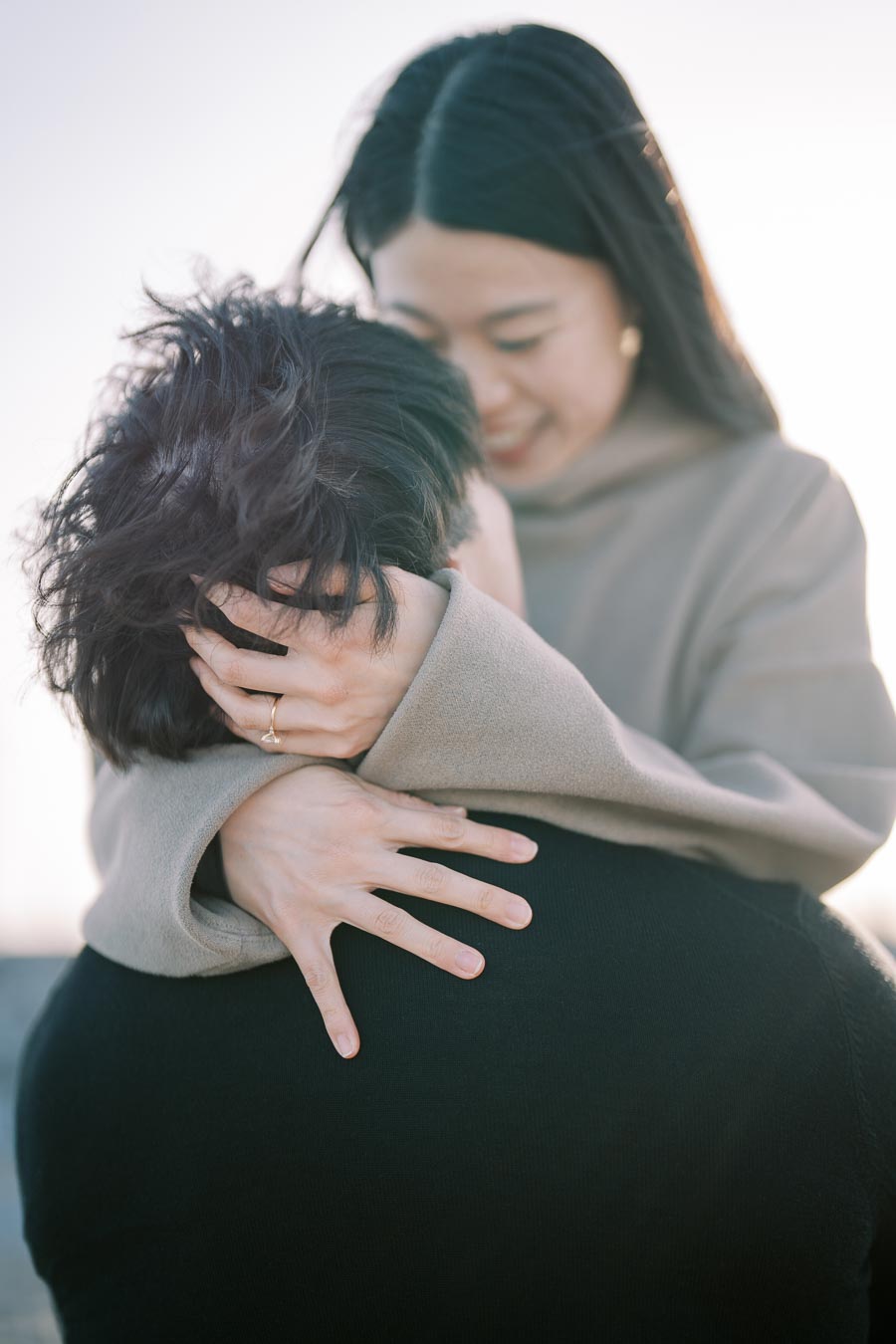 A tender moment captured as a woman embraces someone closely, her hands gently placed on their head, conveying warmth and affection.