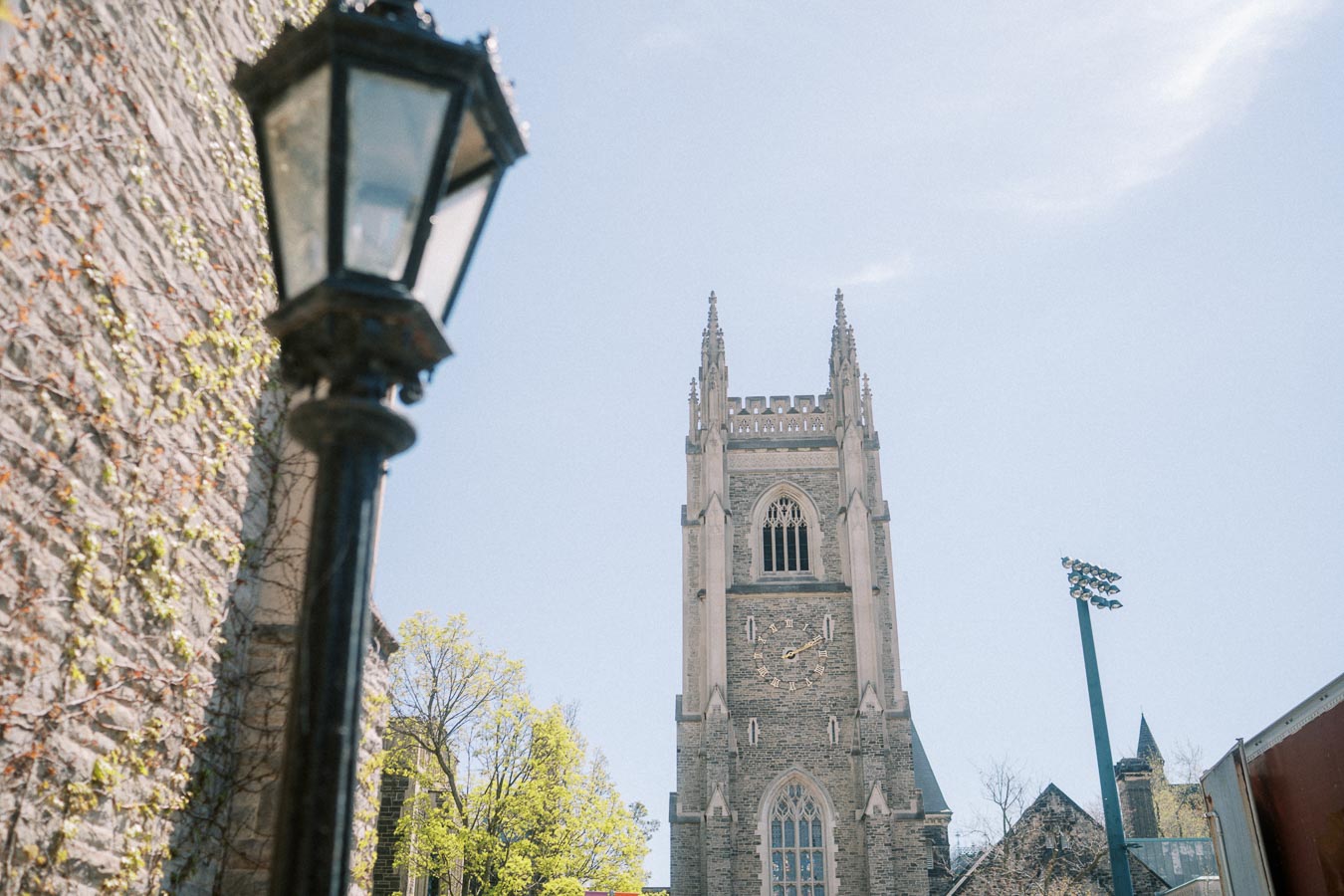 Bell tower of a stone building at the University of Toronto under a clear blue sky.