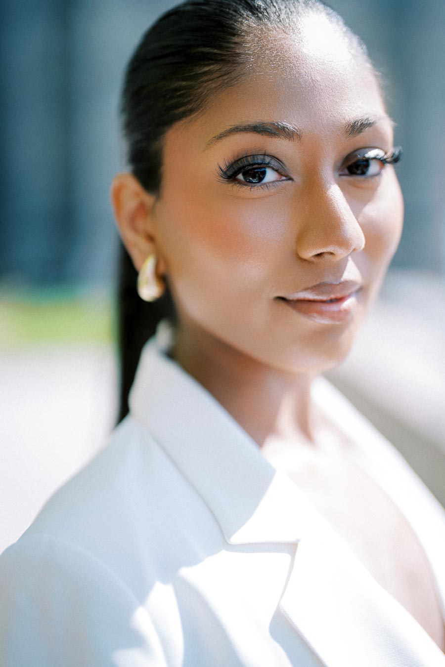 Portrait of a person in a white blazer, outdoors.