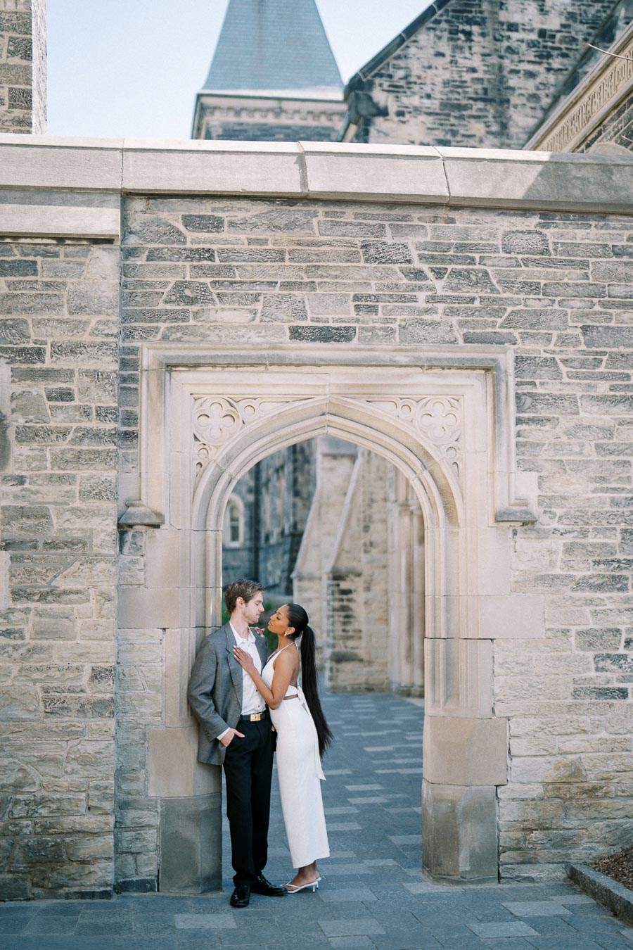 Romantic couple embracing under a historic stone archway in an elegant setting, capturing love and architectural beauty.