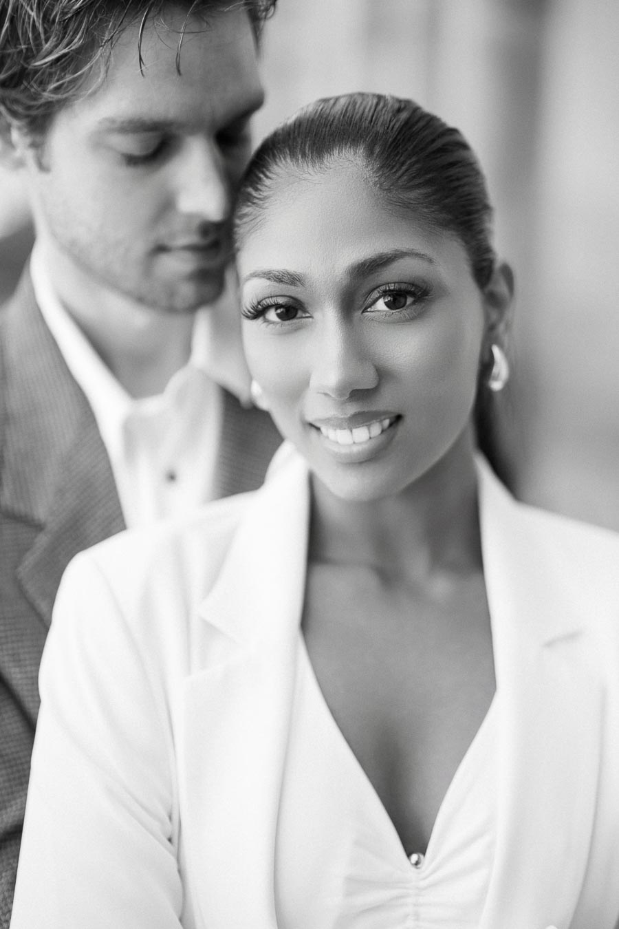 Elegant couple in black and white, woman smiling wearing a blazer, intimate and stylish portrait photography.