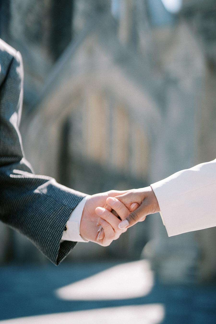 Close-up of two people holding hands, wearing formal attire, symbolizing connection and partnership.