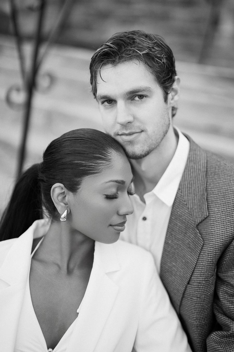 Elegant couple in formal attire, close embrace, black and white portrait.