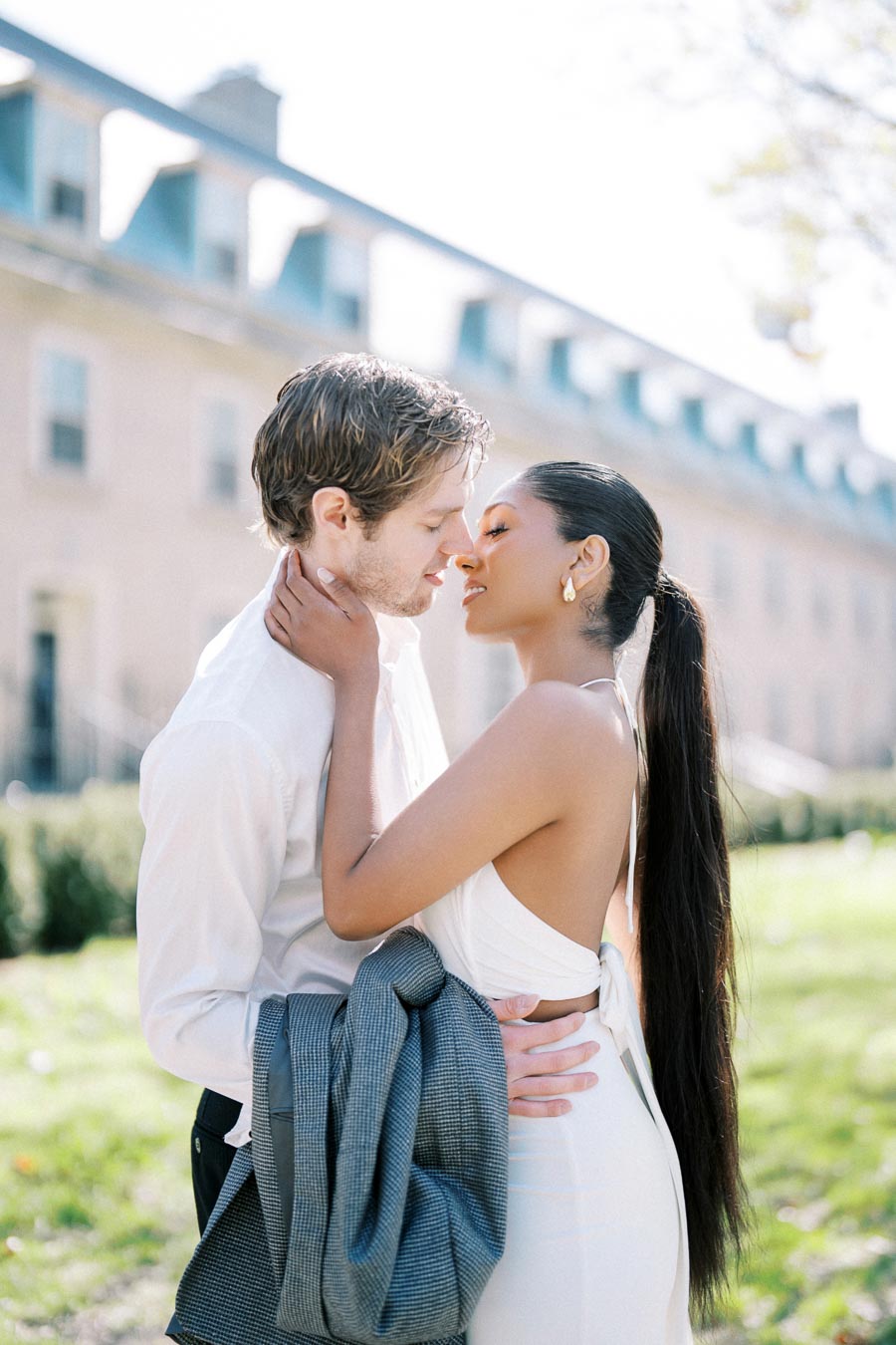 Engaged couple sharing an intimate embrace outside Trinity College at University of Toronto during spring photoshoot