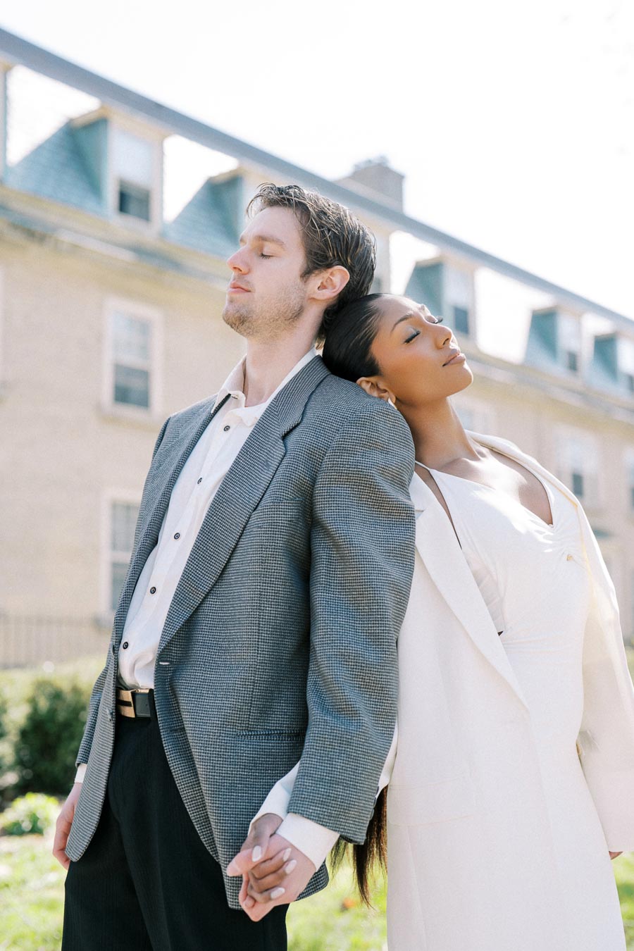 Modern engagement photo of a stylish couple holding hands with eyes closed, leaning on each other in Toronto