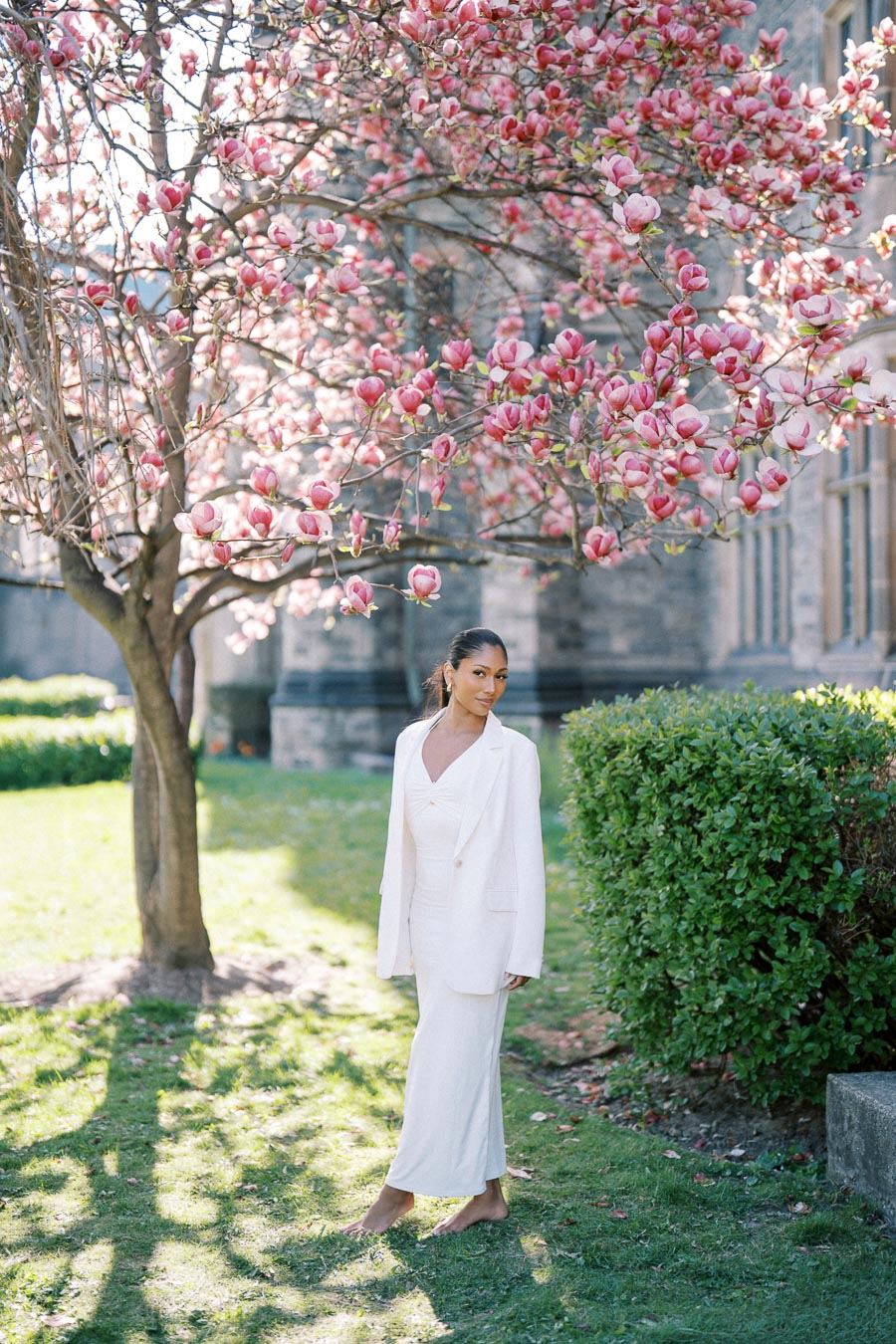 Bride-to-be standing barefoot under blooming magnolia tree at University of Toronto in spring