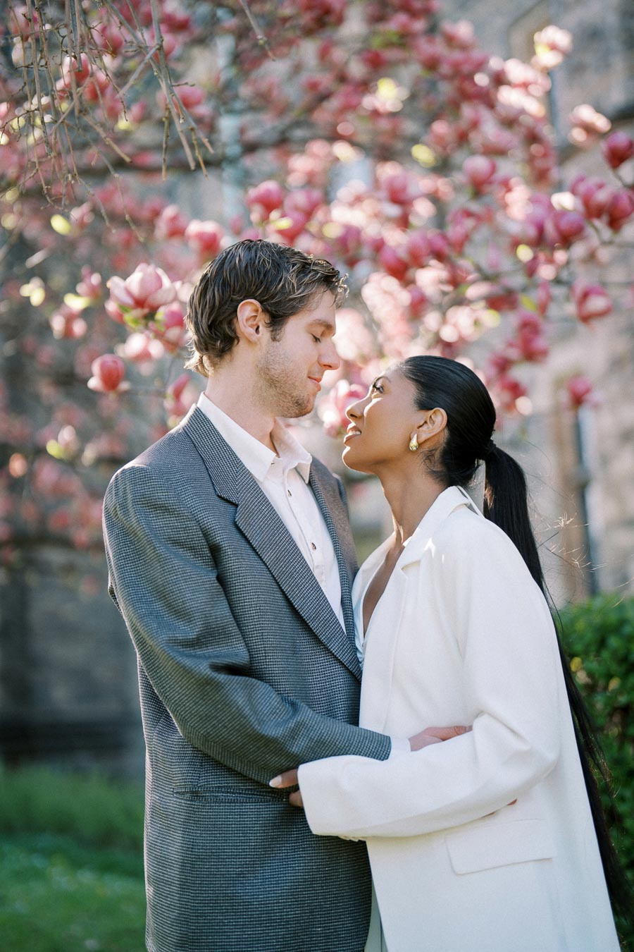 Engaged couple looking into each other's eyes under blooming magnolia tree at University of Toronto