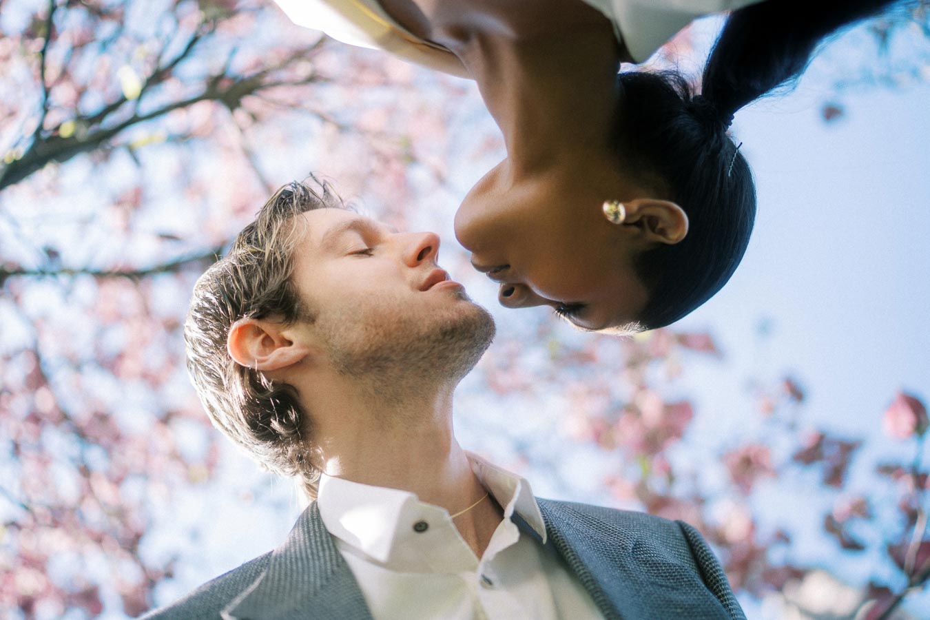 Creative engagement photo of couple about to kiss under magnolia blossoms at University of Toronto