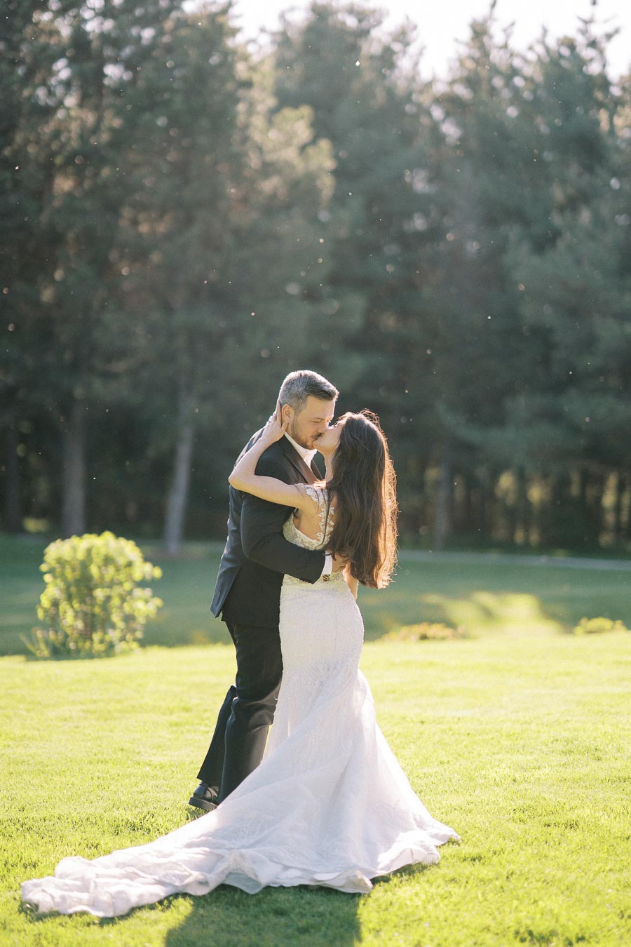 Romantic Moment: Bride and Groom Embrace in Sunlit Garden Wedding Scene