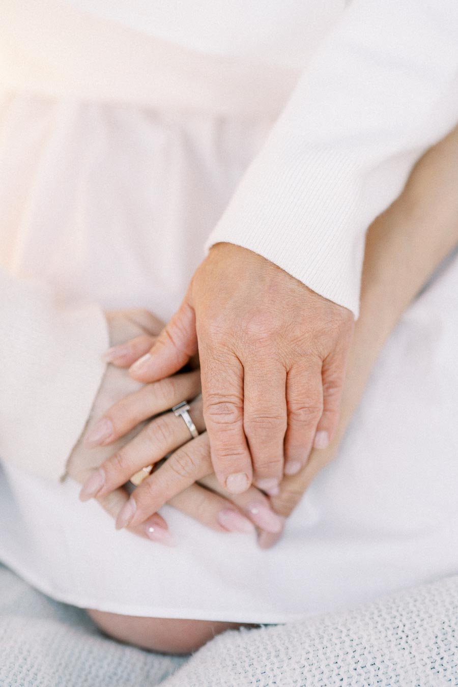 Close-up of two people holding hands, with one person wearing a silver ring and light pink nail polish, symbolizing love and connection.