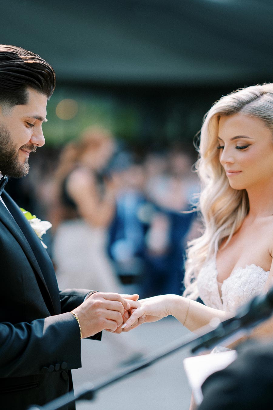 Elegant couple exchanging wedding vows and rings during an outdoor ceremony, symbolizing love and commitment.
