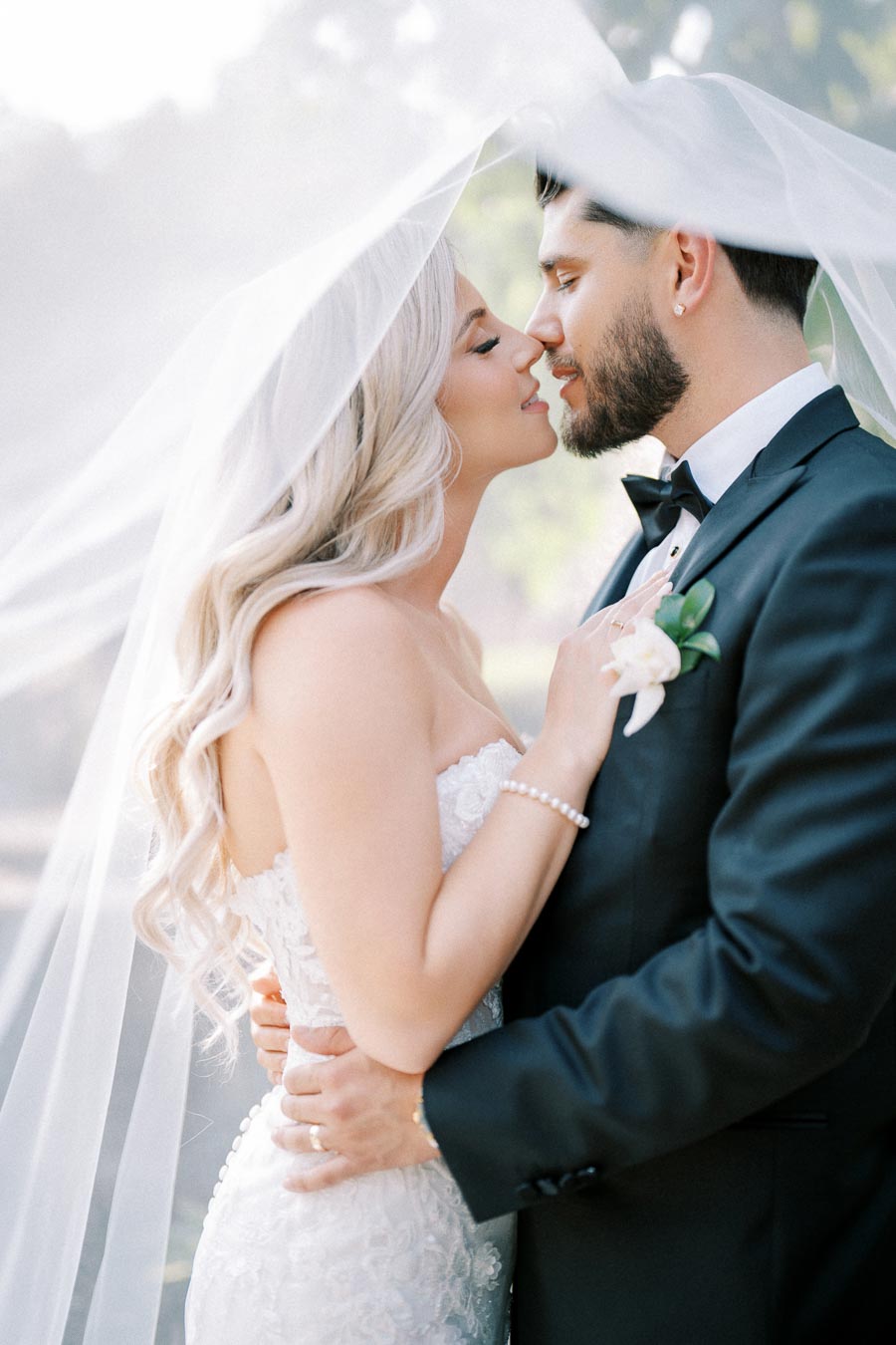A romantic wedding moment with a bride and groom about to kiss under a veil, capturing an intimate and joyful celebration of love.