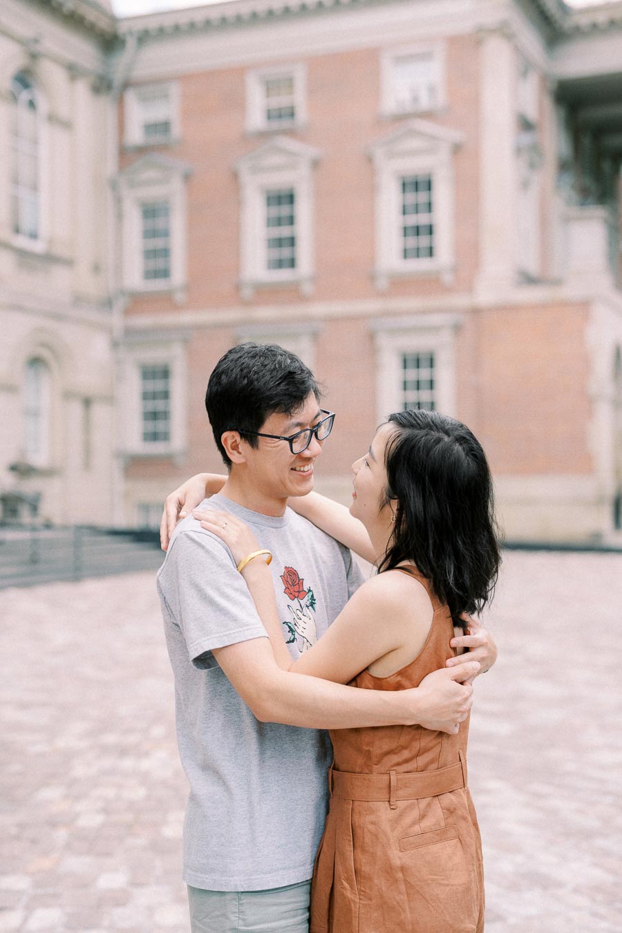 A couple shares a joyful moment in front of a historic building, showcasing their affection and happiness.