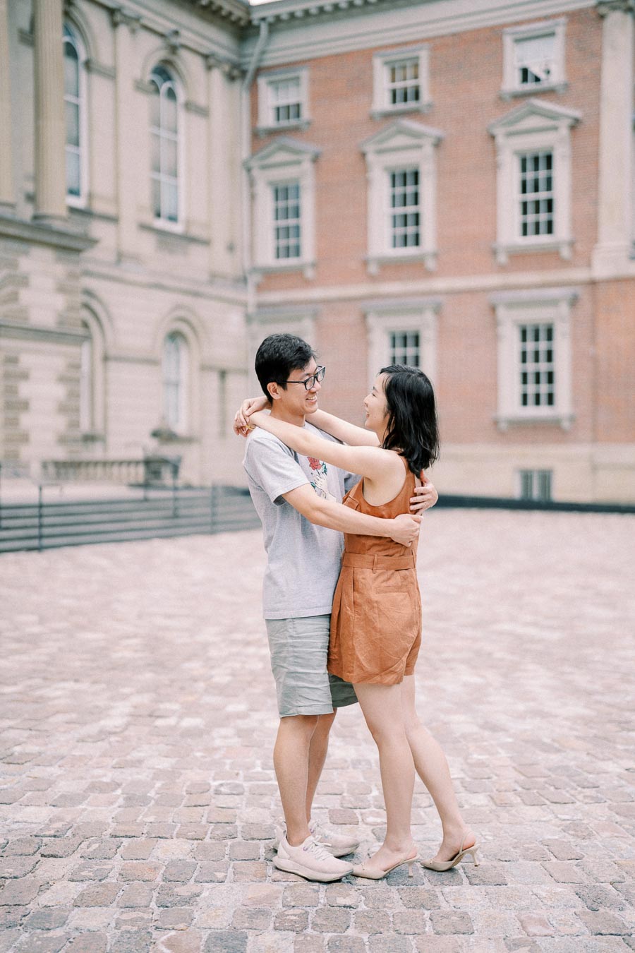 Couple embracing and smiling on cobblestone square in front of Osgoode Hall in Toronto