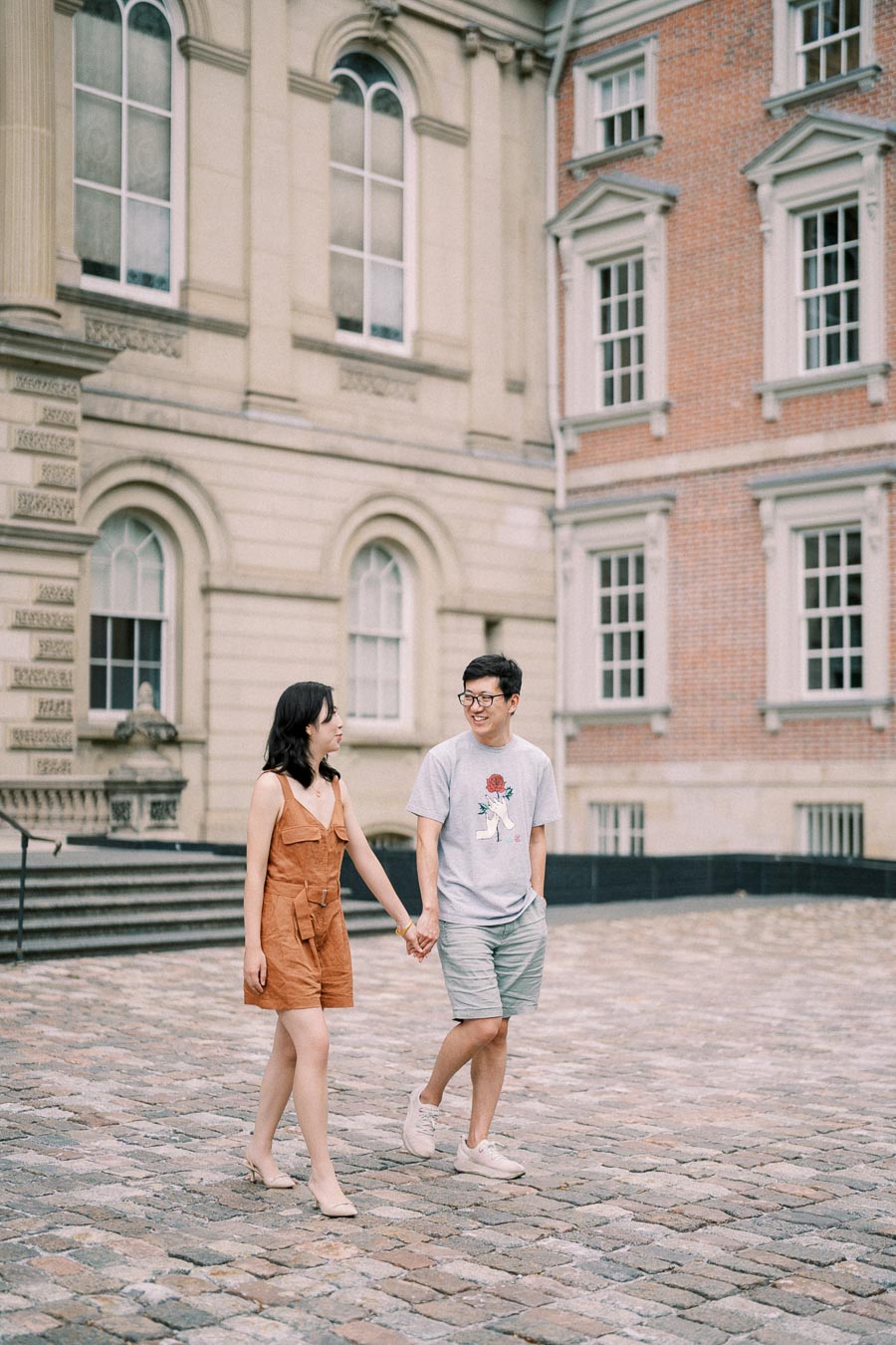 Couple holding hands and walking on cobblestone path at Osgoode Hall in downtown Toronto