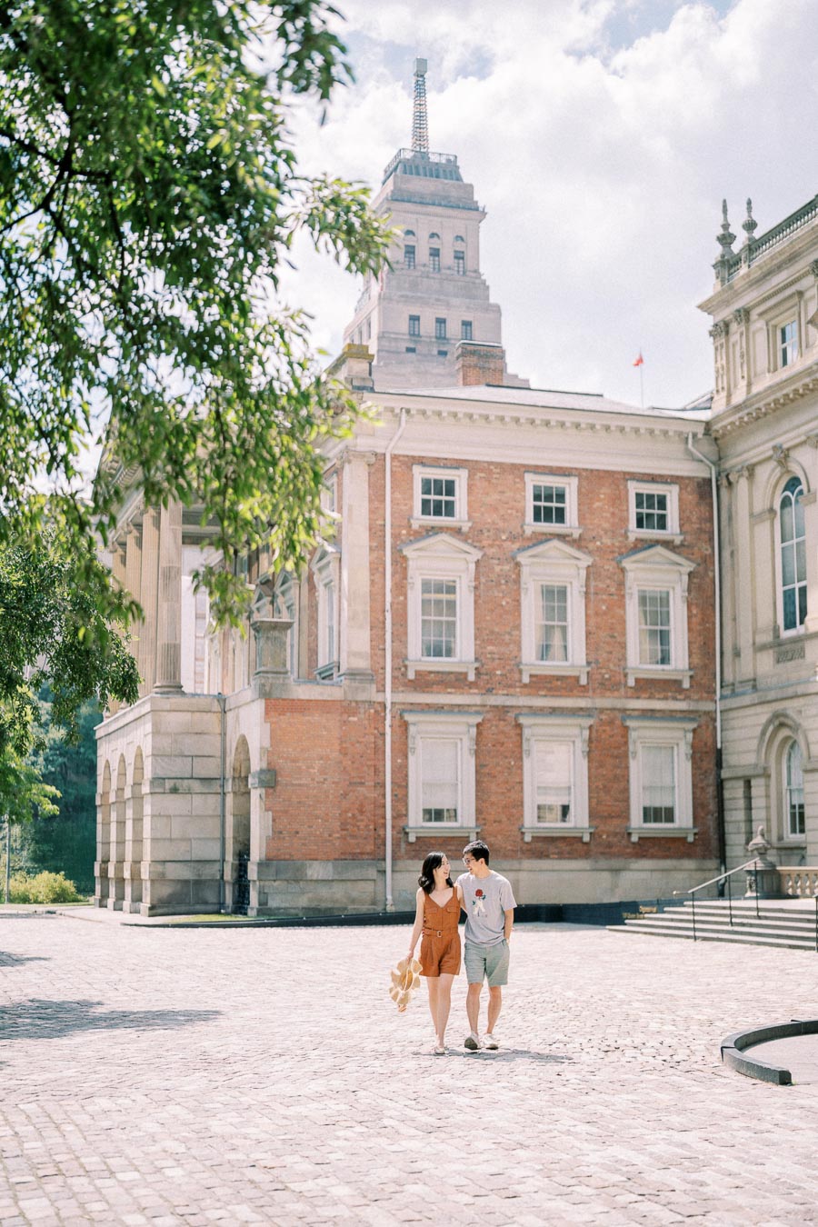 Couple walking on cobblestone courtyard in front of historic Osgoode Hall building in Toronto