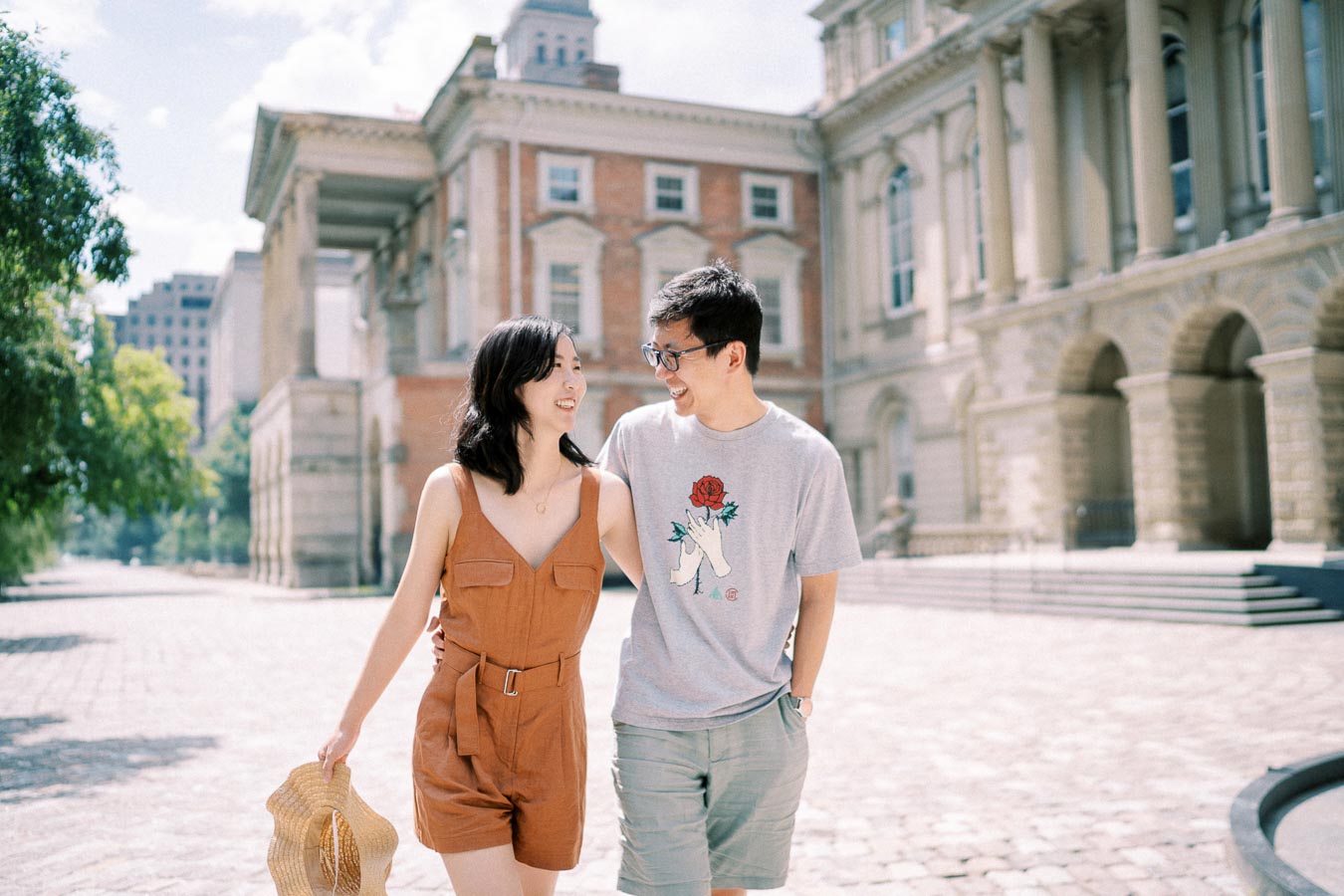 Smiling couple walking hand in hand on a cobblestone street at Osgoode Hall in downtown Toronto