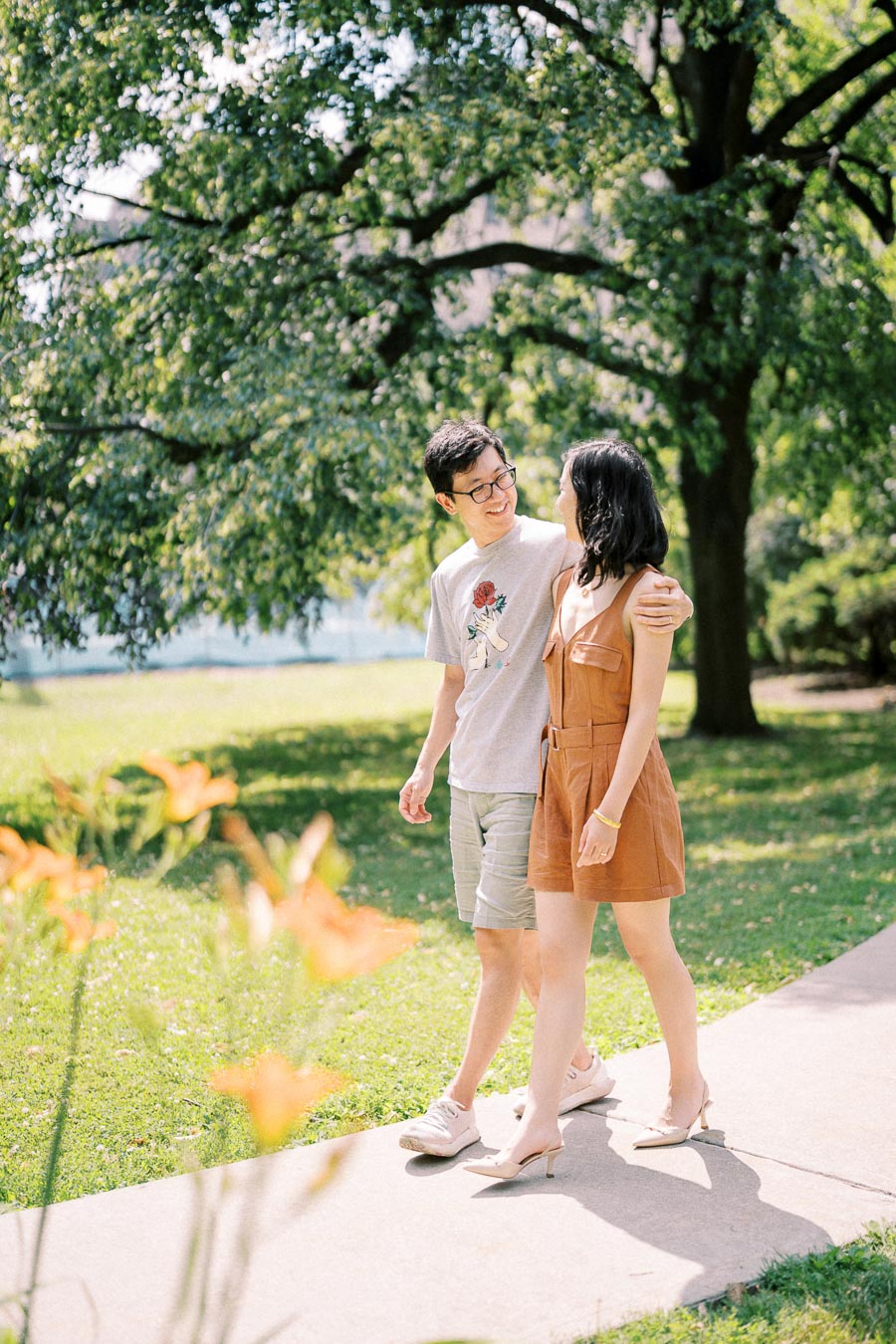 Couple smiling and walking together in a sunny park during a summer photoshoot in Toronto
