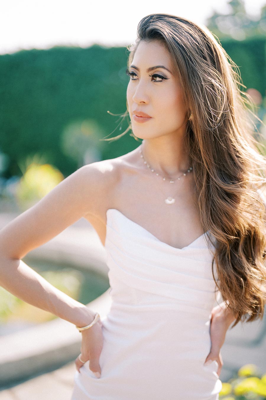 Elegant bride-to-be in strapless white dress posing by the fountain during Parkwood Estate engagement shoot with Toronto photographer