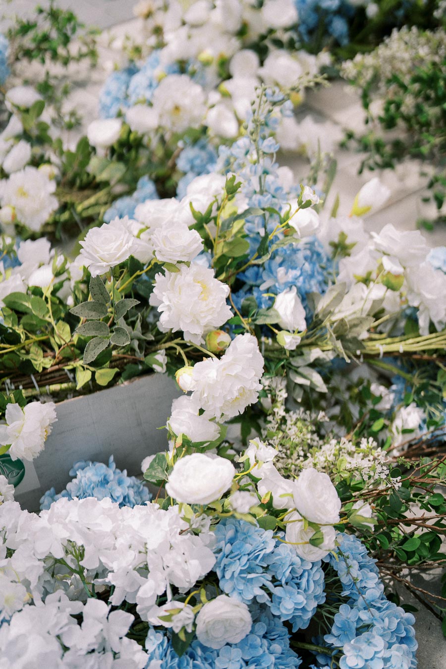 Beautiful arrangement of white roses and blue hydrangeas with green foliage, creating a fresh and elegant floral display perfect for weddings or special events.